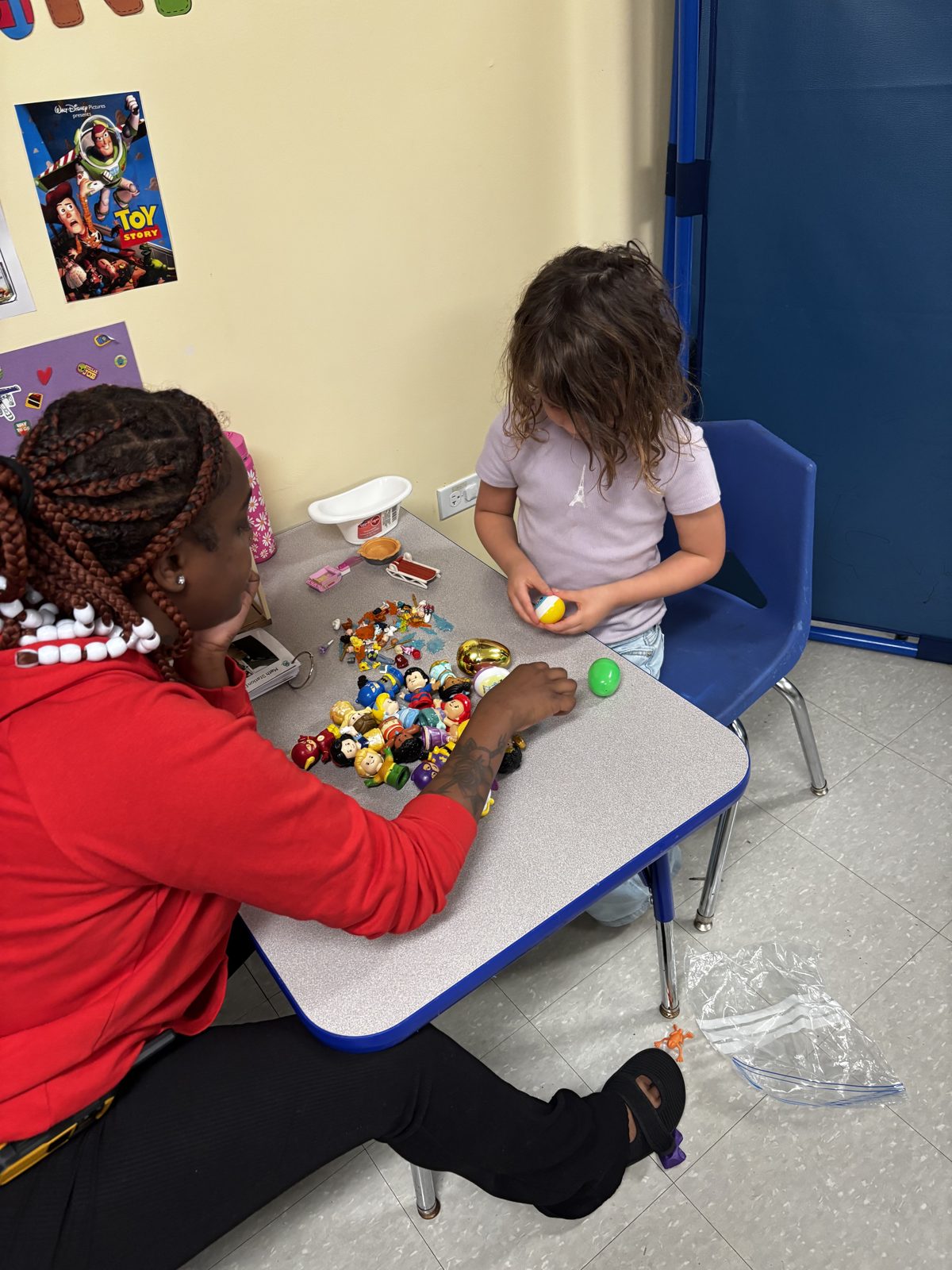 A Soaring Eagle Academy staff member and a student playing with figures at a classroom table.